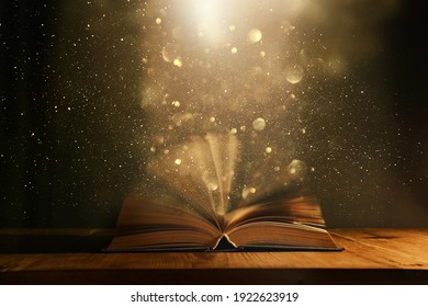 Magical image of open antique book over wooden table with glitter overlay - Powered by Shutterstock