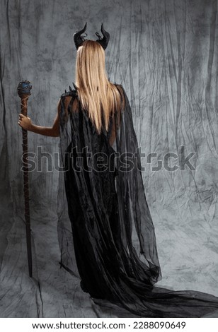 magical lady in a long black dress and with demon horns, back view