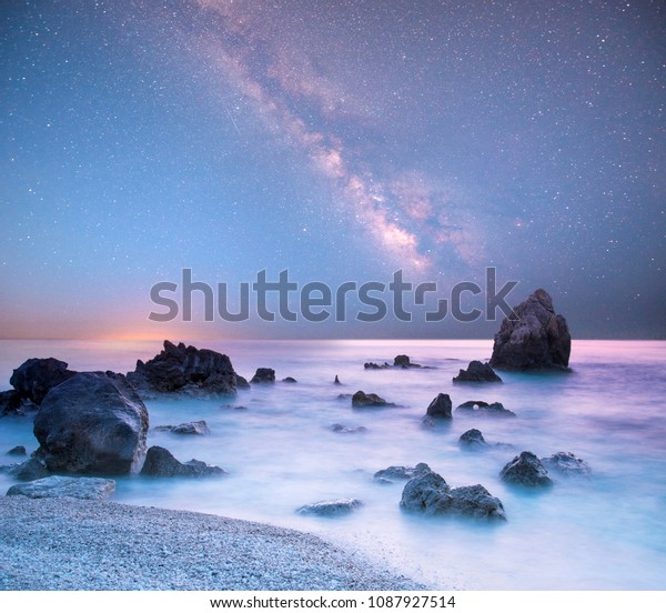 magical mystical beautiful charming landscape\
with waves and stones in the middle of the sea on the coast against\
the background of the stars and the Milky Way. (meditation,\
antistress - concept)