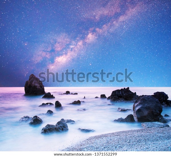 magical mystical beautiful charming landscape\
with waves and stones in the middle of the sea on the coast against\
the background of the stars and the Milky Way. (meditation,\
relaxation - concept)