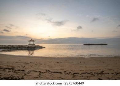 Magical sunrise with clouds in the sky. Dramatic sky at Sanur beach, Denpasar in Bali. Temple in the calm sea in the morning. Tropical landscape shot - Powered by Shutterstock