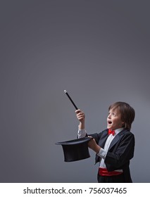 Magician boy performing with magic wand and hard hat - looking up to copy space