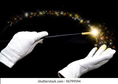 Magician hands in white gloves holding magic wand and casting spell