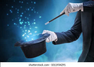 Magician or illusionist is showing magic trick. Blue stage light in background.