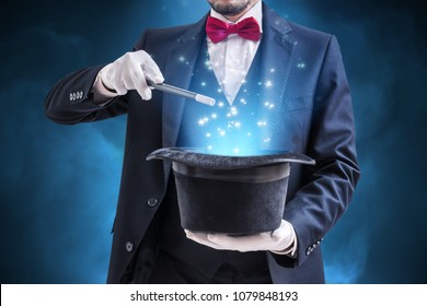 Magician or illusionist is showing magic trick. Blue stage light in background. - Shutterstock ID 1079848193