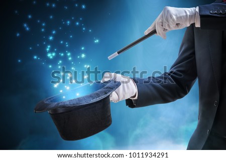 Magician or illusionist is showing magic trick. Blue stage light in background.