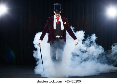 Magician, Juggler man, Funny person, Black magic, Illusion standing on the stage with a cane of beautiful light. shrouded in a beautiful mysterious smoke