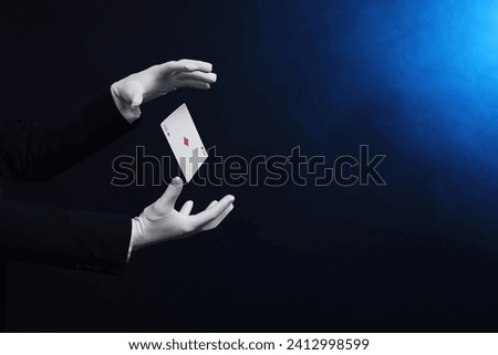 Magician showing trick with card on dark background, closeup. Space for text