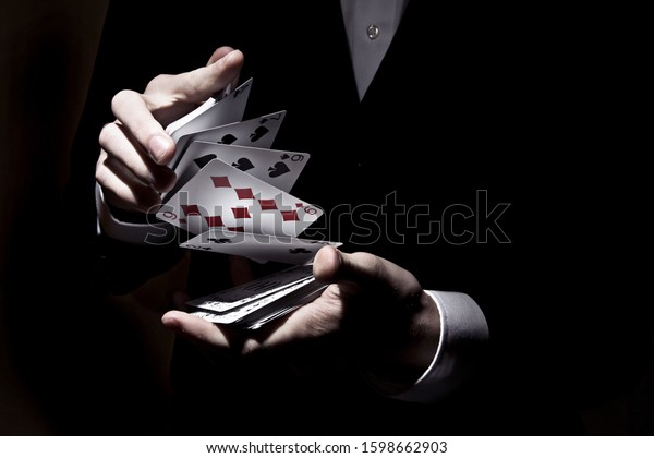 A\
magician shuffling cards with the spotlight on\
it