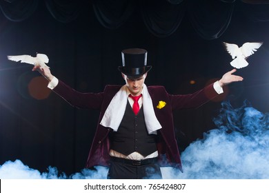 The magician with a two flying white Doves. on a black background shrouded in a beautiful mysterious smoke - Powered by Shutterstock