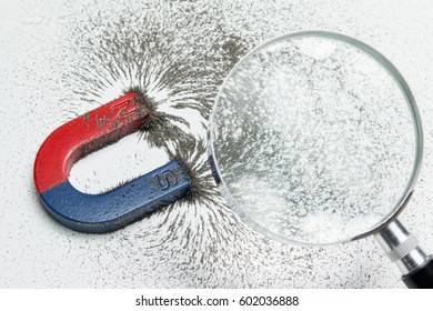 Magnet Attracting Iron Power With Magnetic Force Through Magnifying Glass. Scientific Experiment In Science Class In School.