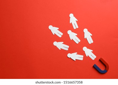 Magnet attracting paper people on red background, flat lay. Space for text