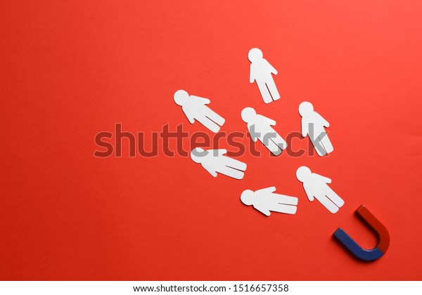 Magnet attracting paper people on red background,\
flat lay. Space for text
