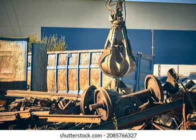 Magnet crane unloads scrap metal from truck. Hand of grabber excavator unloading recycle metal waste from truck. Clamshell at scrap metal yard - Shutterstock ID 2085766327