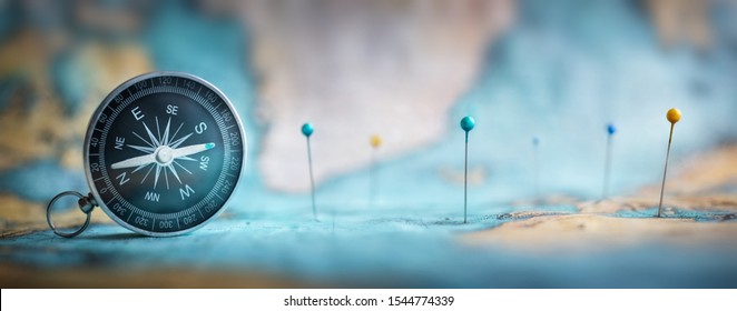 Magnetic compass  and location marking with a pin on routes on world map. Adventure, discovery, navigation, communication, logistics, geography, transport and travel theme concept background.