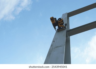 Magnetic drill mounted on a steel beam. For safety, it is securely attached to the beam with a magnet and a metal chain. This is a portable drill with a magnetic base. - Powered by Shutterstock