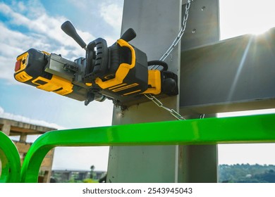 Magnetic drill mounted on a steel beam. For safety, it is securely attached to the beam with a magnet and a metal chain. This is a portable drill with a magnetic base. - Powered by Shutterstock