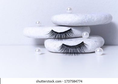 Magnetic fake artificial eyelashes and pearl on white stones. Home eyelash extension, cosmetology tool concept, beauty treatment, improving physical appearance