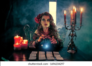 Magnificent fortune teller woman reading future on magical crystal ball and tarot cards.