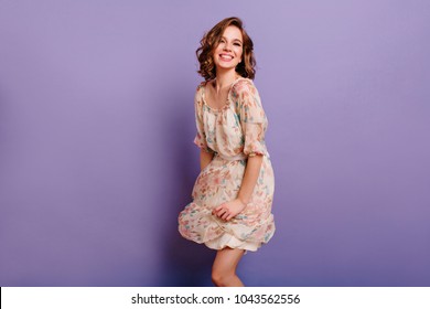 Magnificent Girl With Light-brown Curly Hair Dancing With Smile In Purple Studio. Indoor Portrait Of Inspired Caucasian Lady In Romantic Outfit Expressing Happy Emotions.