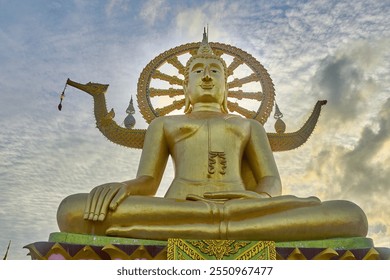 A magnificent golden Buddha statue sits serenely at Wat Phra Yai in Koh Samui, Thailand. This stunning landmark features intricate designs and a vibrant backdrop. - Powered by Shutterstock