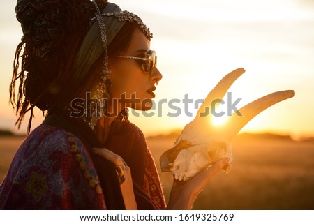 Magnificent gypsy fortune teller with a skull in the rays of the sunset. 
