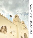 A magnificent mosque with distinctive Islamic architecture, beige-colored walls, and towering domes. Ornament details on windows and walls add to the beauty of the building.