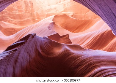 Magnificent nature sun filters into Lower Antelope Canyon Page Arizona USA while the shapes and swirls create and abstract nature image and silica in sandstone reflects some intense colors. - Powered by Shutterstock