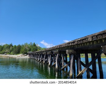 The magnificent Old bridge at Summerville beach running through it. The bridge's reflection is shown perfectly above the water. It's blocked so cars down drive over the decaying wooden structure.