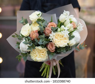 Magnificent rustic bouquet of tulips, roses and other flowers and herbs. Young woman holding rustic beautiful bouquet of interesting flowers.