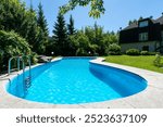 A magnificent swimming pool on the lawn of a private house on a clear sunny day. Dense 
greenery surrounds the courtyard.