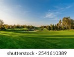 Magnificent view of the golf course with bright green grass and ponds on a clear autumn day.