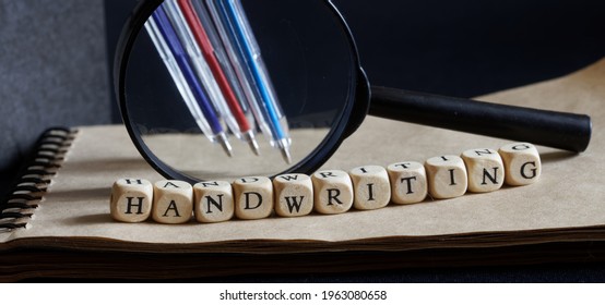 Magnifier, Ballpoint Pens, Notepad And The Inscription Handwriting On A Dark Background. Concept Of Handwriting Examination And Automatic Handwriting Recognition. Close-up