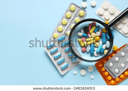Magnifier with different pills on blue background