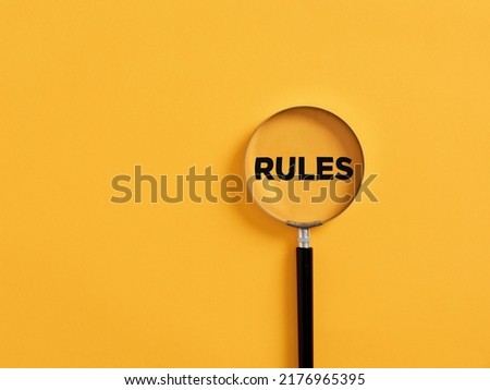 Magnifier focuses on the word rules. Analyzing or following the rules concept.