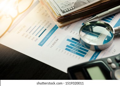 Magnifier glass calculator and financial data on businessman 's desk for analysis and find the best stock from stock market.