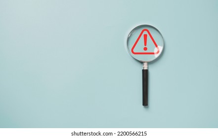 Magnifier glass with red triangle caution warning sign for notification error and maintenance concept.