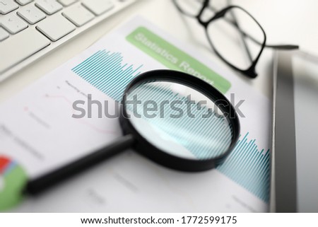 Magnifier glasses lie on table with documents in office. Development and support of small and medium business concept