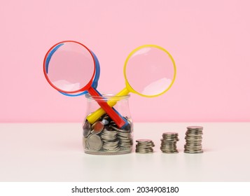 Magnifier And White Coins On The Table. Income Growth Concept, High Percentage Of Investment. Search For New Sources Of Income, Subsidy