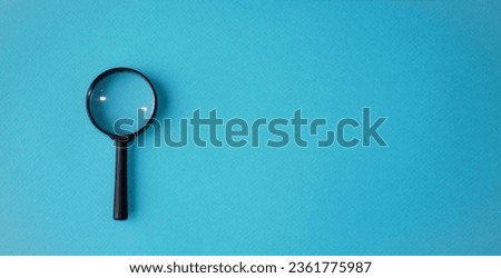 Magnifying glass, magnifying glass in a black frame on a blue background.  Concept research, objects magnification.  Flat top view.  Space for copying text.