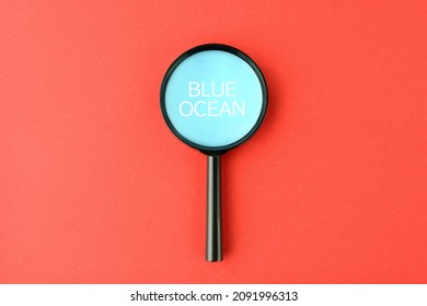 Magnifying glass with blue ocean screen on red paper background