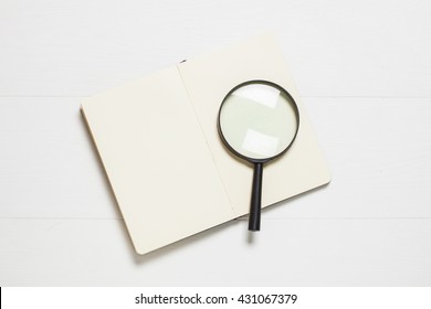 Magnifying Glass And Book On Wooden Table. Top View.