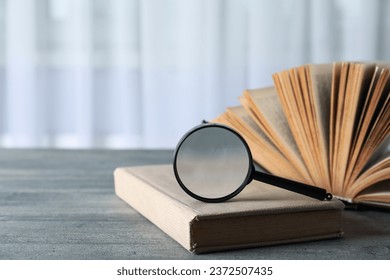 Magnifying glass and books on wooden table on light background, space for text - Powered by Shutterstock