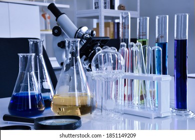 A Magnifying Glass And Chemistry Lab Glassware Set Are Placed On A Stainless Steel Table.