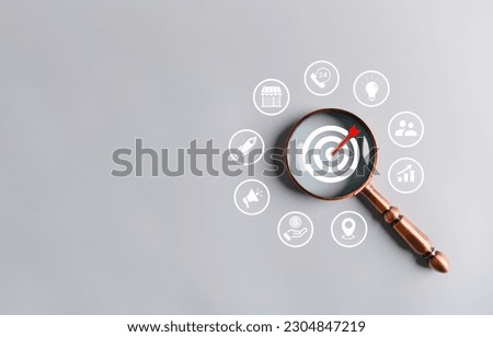 Magnifying glass magnifying the dartboard target on gray background. Business startup marketing announcement stock and investment market share idea and Business owner interpreter open new shop concept