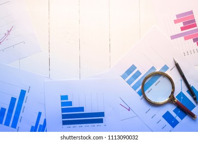 Magnifying glass and documents with analytics data lying on table,selective focus