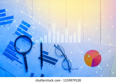 Magnifying glass and documents with analytics data lying on table,selective focus