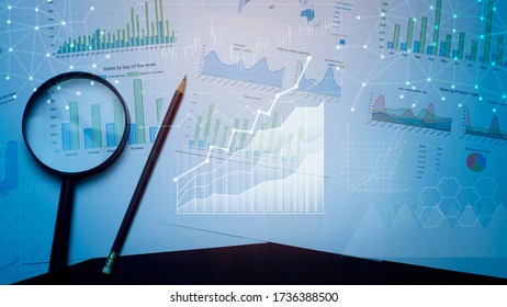 Magnifying glass and documents with analytics data lying on table