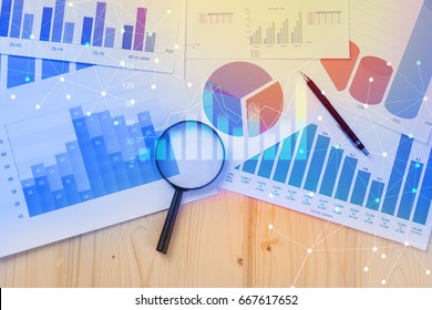 Magnifying glass and documents with analytics data lying on table,selective focus