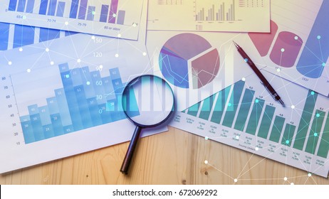 Magnifying glass and documents with analytics data lying on table,selective focus - Shutterstock ID 672069292